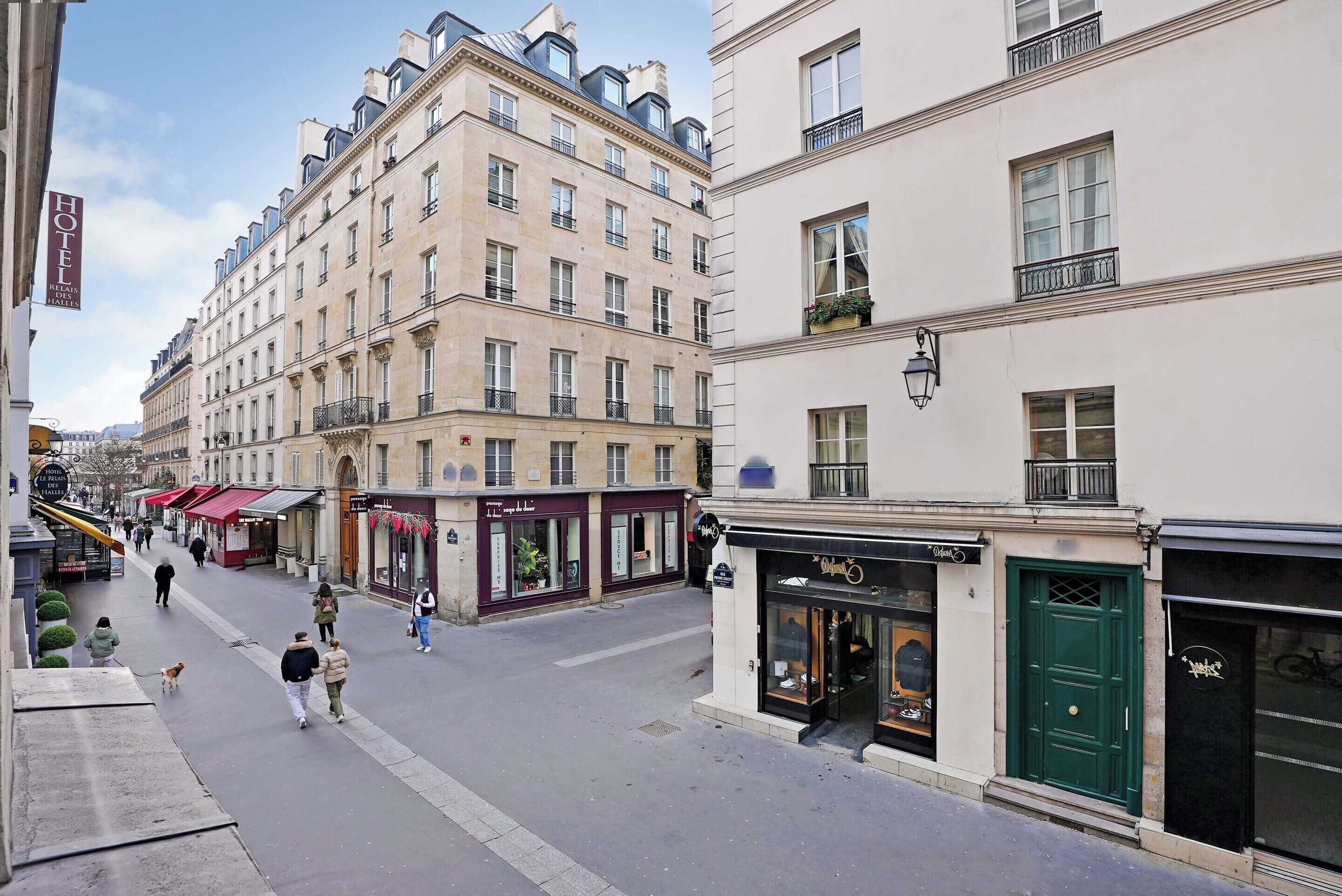Straßenansicht eines Pariser Hotels mit einer klassischen Fassade, mehreren Etagen und einer grünen Tür.