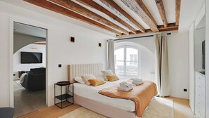 Ein Schlafzimmer mit Bett, Fernseher und einem Fenster mit Vorhängen.