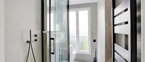 A modern bathroom with a glass shower enclosure, a toilet, and a bidet.