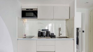 Eine kleine Küche mit eingebautem Ofen, einer Kaffeemaschine und einem Spülbecken.
