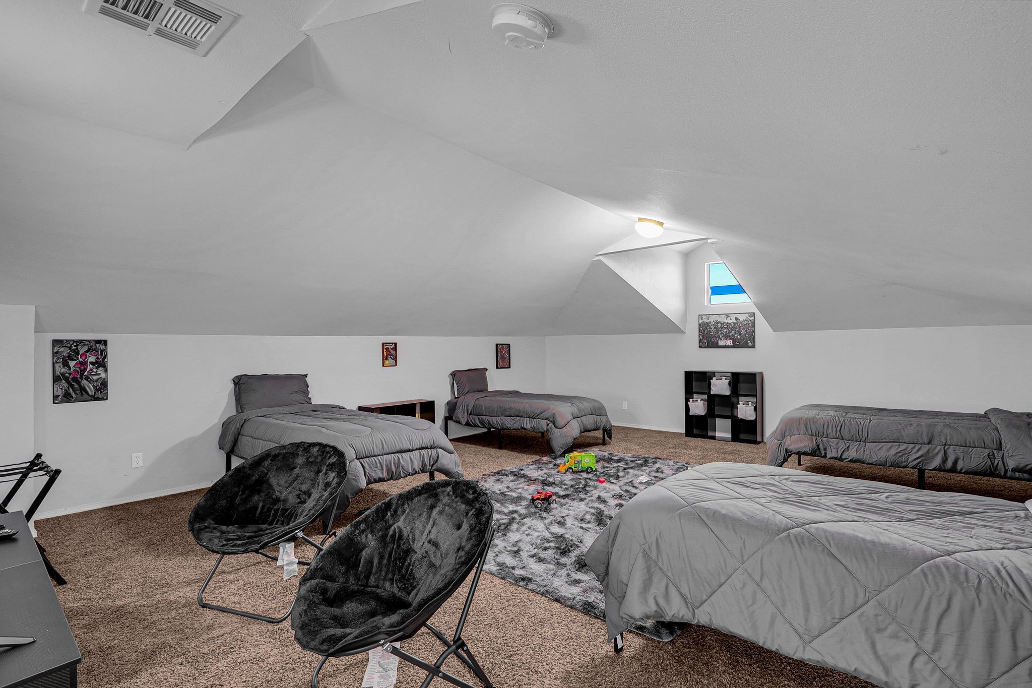 Un amplio dormitorio en el ático con dos camas, un escritorio y una silla.