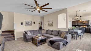 A spacious living room with a sectional sofa, a coffee table, and a ceiling fan. - Huge Oasis Retreat>Arcade>Pool Table>Heated Pool & Spa>Super H on AirBB (El Paso)