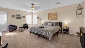 A bedroom with a bed, two bedside tables, a chair, a small table, and a ceiling fan. - Huge Oasis Retreat>Arcade>Pool Table>Heated Pool & Spa>Super H on AirBB (El Paso)