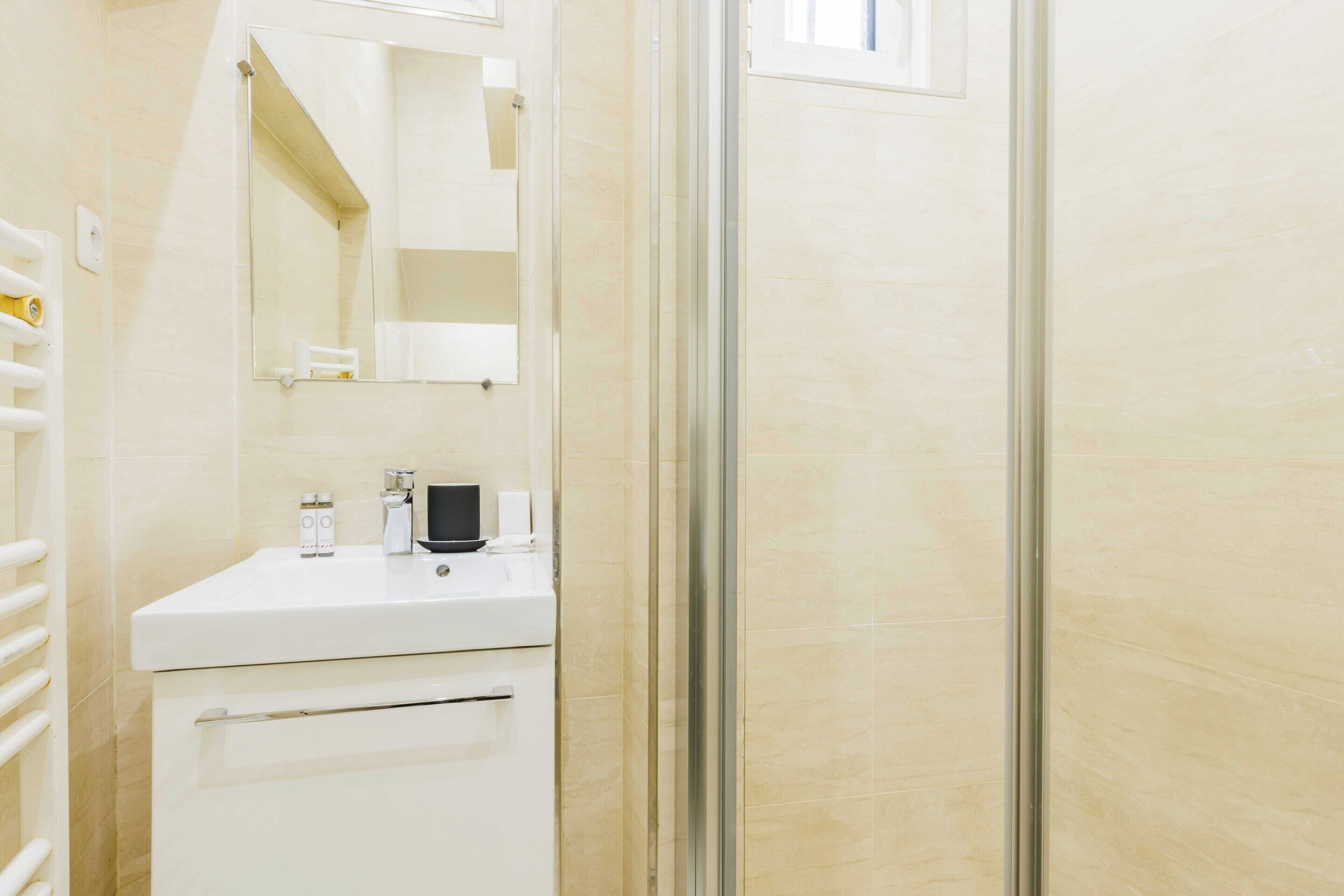 A bathroom with a white sink, a mirror, and a glass shower enclosure.