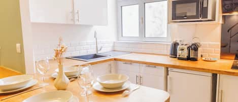 A modern kitchen with white cabinets, a wooden countertop, a microwave, and a dishwasher.