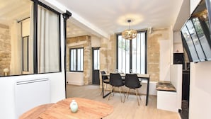 A modern dining area with a wooden table, black chairs, and a chandelier. - Cozy Apartment - 1br/4p - Sentier (Paris)