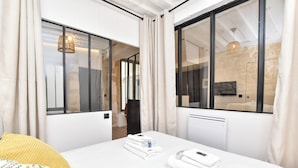 A hotel room with a large bed, a bathroom with a mirror, and a view of the outside. - Cozy Apartment - 1br/4p - Sentier (Paris)