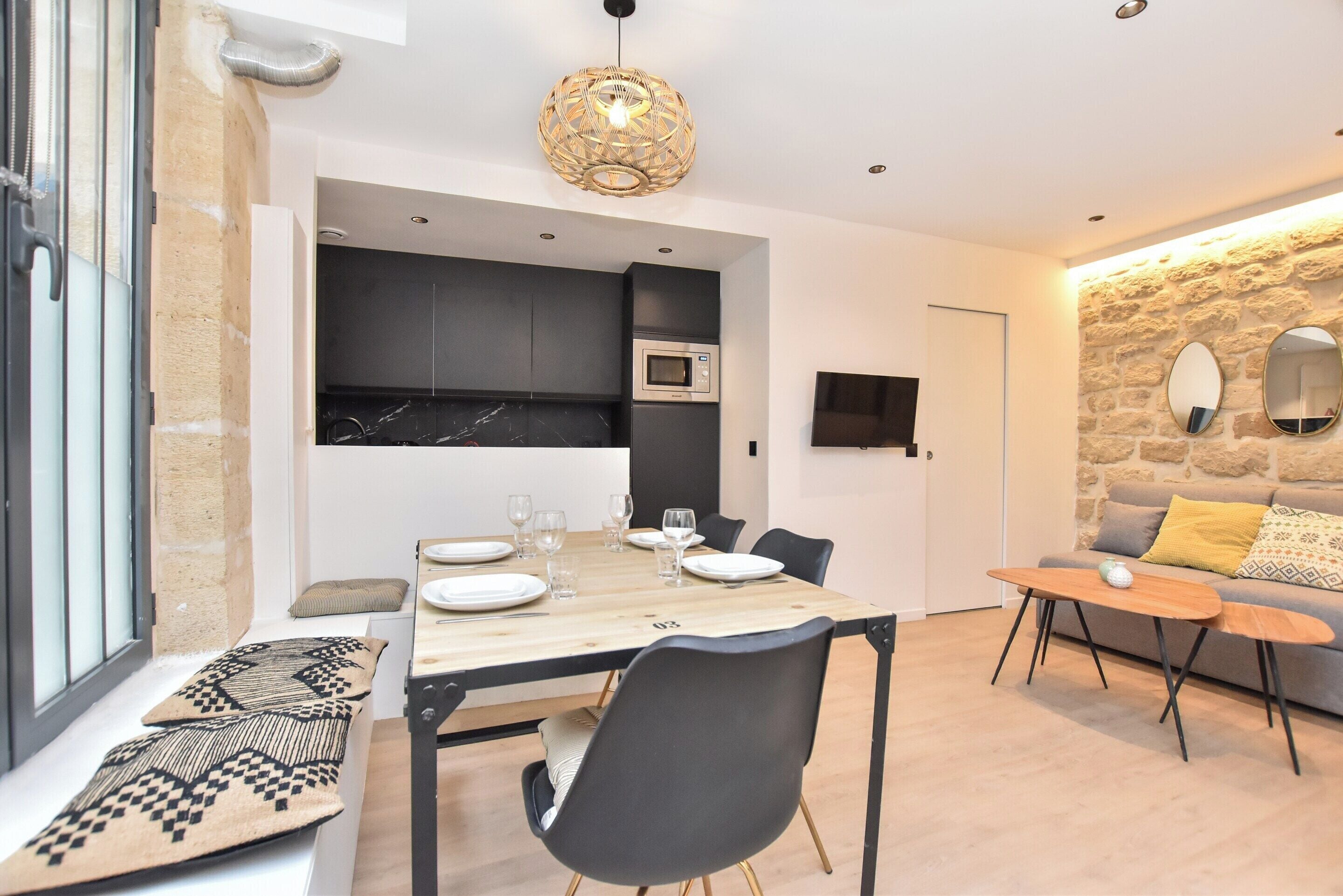 Une cuisine moderne avec des meubles de couleur sombre, un four à micro-ondes et un coin repas comprenant une table et des chaises en bois.