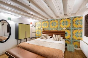 Une chambre avec un plafond en bois, un lit doté d’une tête de lit marron et un mur recouvert de carreaux colorés à motifs.