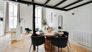 A dining area with a round wooden table, four black chairs, and a white radiator on the wall. - Charming Apartment - 1br/5p - Quartier du Mail (Paris)