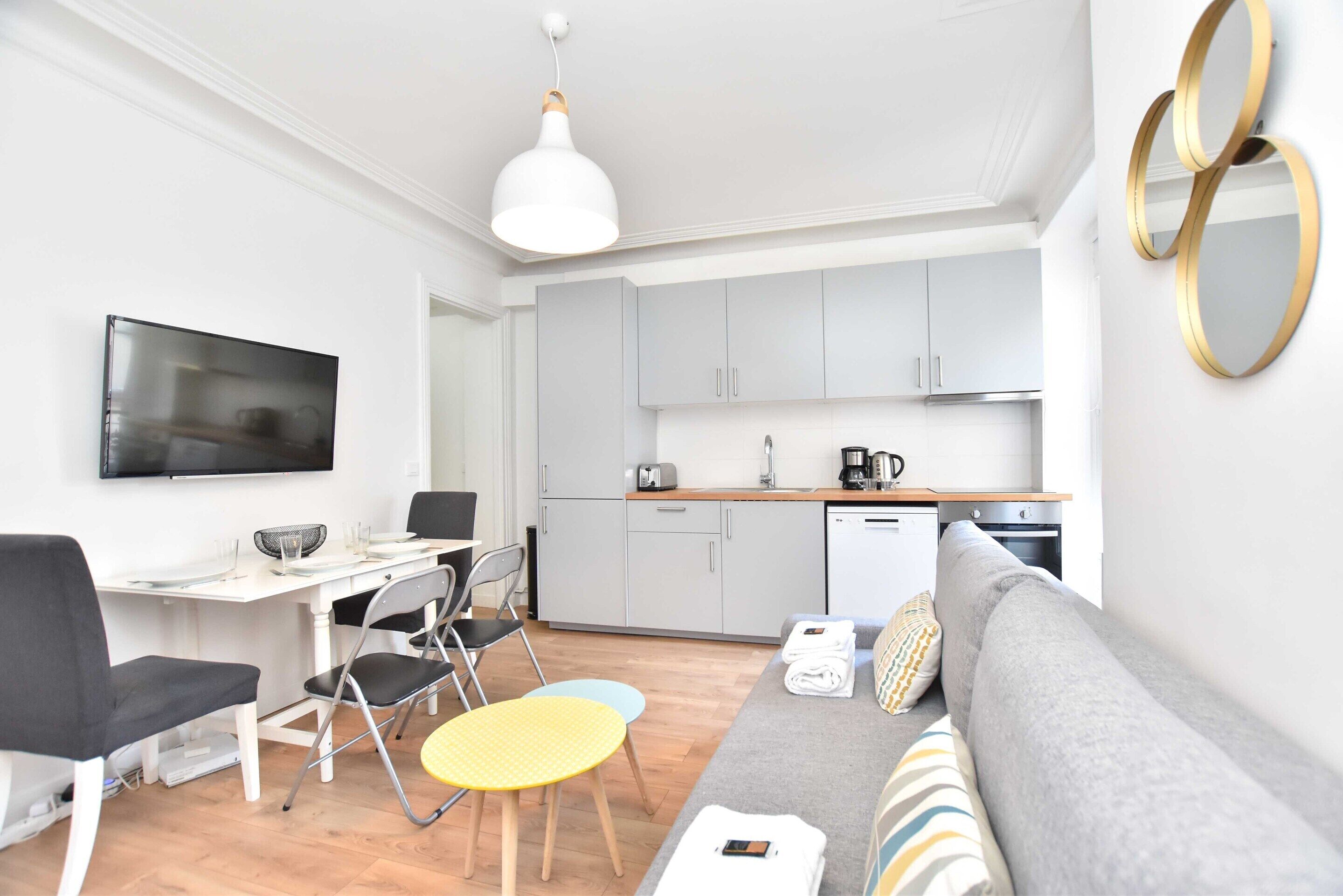 Un espacio habitable moderno y funcional con comedor, kitchenette y sofá.
