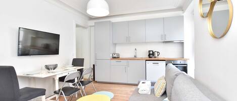 Un espacio habitable moderno y funcional con comedor, kitchenette y sofá.