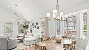 A spacious dining area with a wooden table and chairs, a chandelier, and large windows with curtains. - Pools*Bikes*Pools*Walk2beach (Santa Rosa Beach)