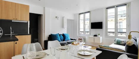 A modern living space with a dining area, kitchen, and seating area.