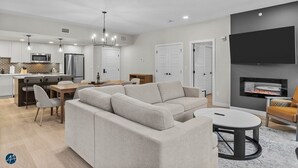 A modern living room with a sectional sofa, a dining area with a table and chairs, a kitchen with a microwave and refrigerator, and a fireplace. - 3 Bed/2 Bath Sparrowhawk Lodge-TopFloor-Creekside (Dead Man's Flats)