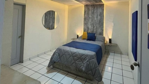 Ein Schlafzimmer mit einem Bett, einem runden Spiegel und einem an der Wand befestigten Fernseher.