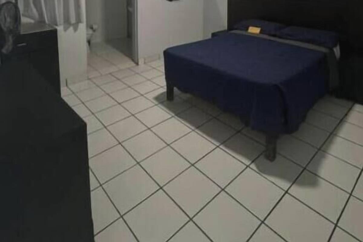Un dormitorio con una cama, un escritorio, una silla, un espejo redondo y una puerta que da a otra habitación.