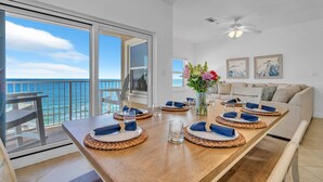 A dining area with a view of the ocean, a ceiling fan, and a sofa in the background. - Emerald Dunes 501*Penthouse*Pool*Hot Tub*Gulf View (Destin)