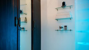 A room with a dark wooden door, glass shelves with towels, and a small decorative item on the wall. - Ravana Egyptians Villa (Chennai)