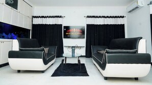 A modern living room with two black and white sofas, a small round table, and a TV mounted on the wall. - Ravana Egyptians Villa (Chennai)