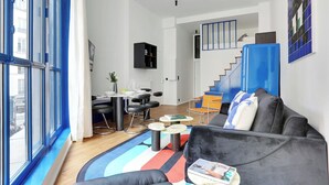 Una sala de estar moderna con un sofá, una mesa de centro y un comedor con mesa y sillas.