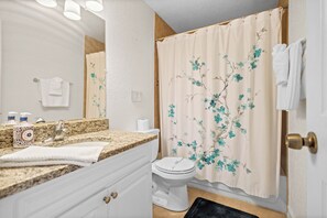 A bathroom with a sink, toilet, and shower curtain. - Azure 2BR/2BA Condo , Heated Pool Near Siesta (Sarasota)