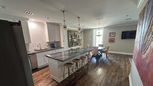 A modern kitchen with a large island, bar stools, and pendant lighting.
