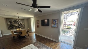 A spacious living room with hardwood floors, a ceiling fan, a dining area with a table and chairs, and a large painting on the wall.