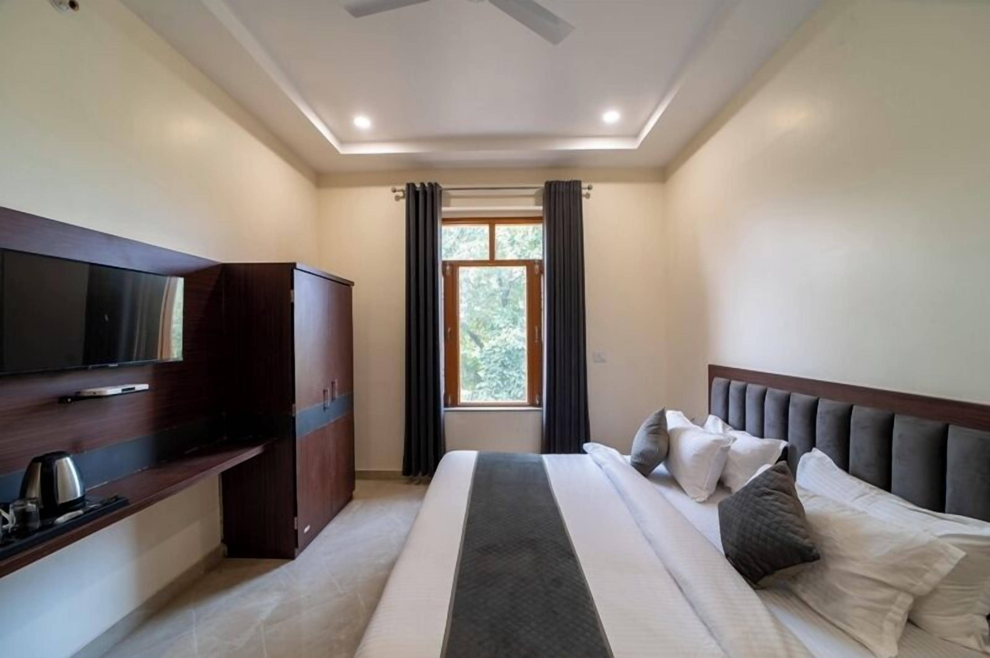 A hotel room with a bed, a TV, a wardrobe, and a window with curtains.