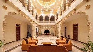 A spacious lobby with a central seating area, ornate arches, and a chandelier. - Joy Bagh Resort  (Pushkar)