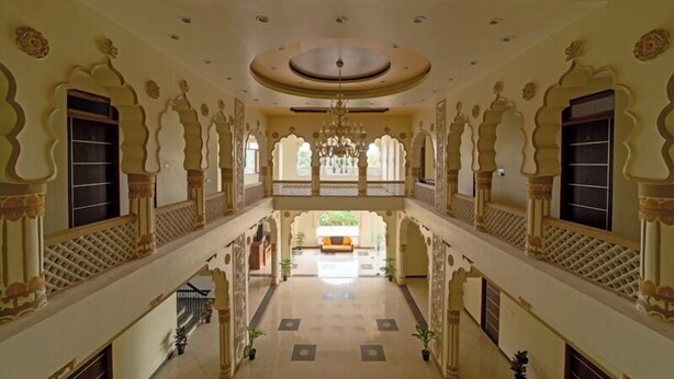 A spacious, ornate interior with a central open area, decorative arches, and a chandelier. - Joy Bagh Resort  (Pushkar)