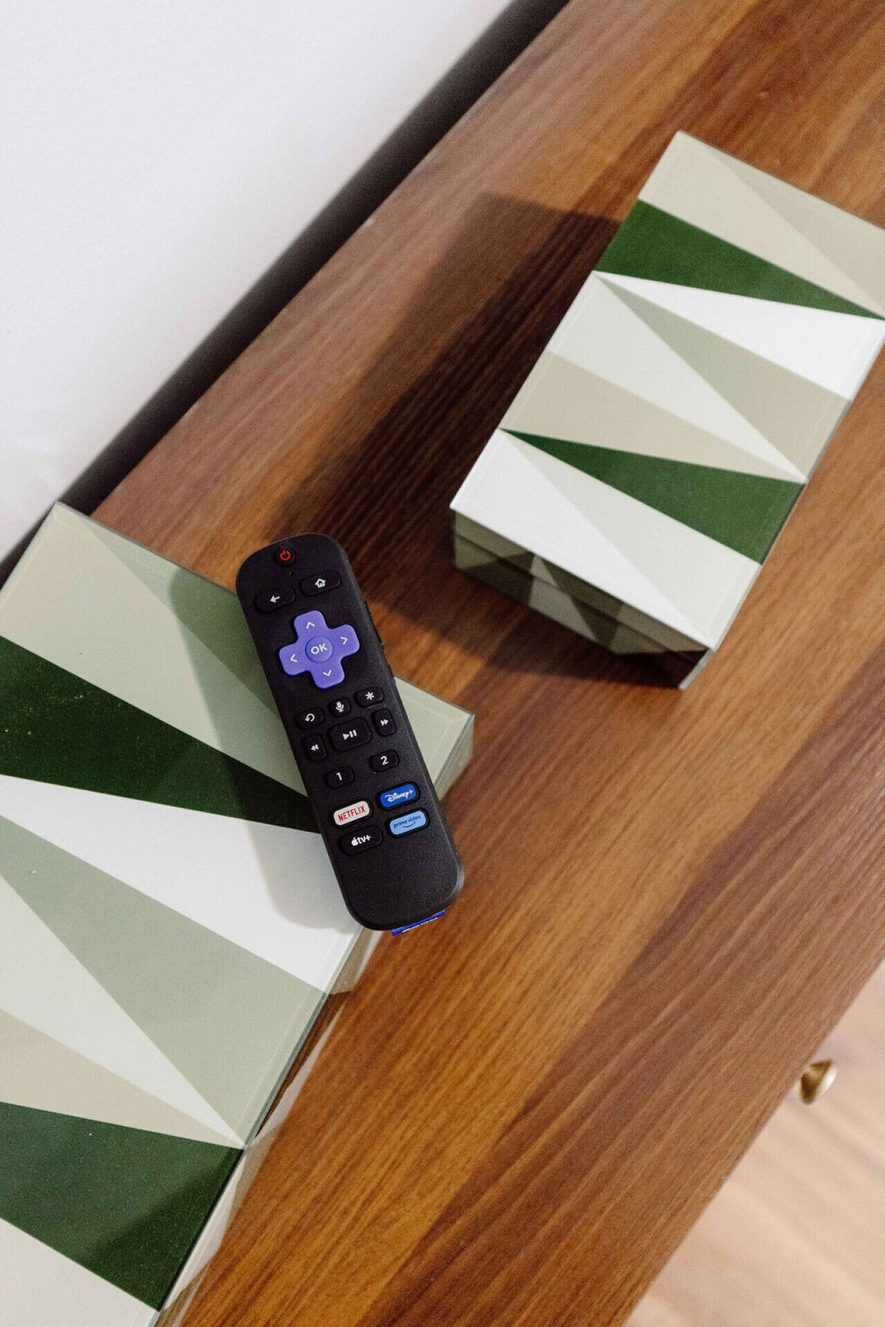 A remote control on a wooden surface with striped boxes.
