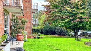 A well-maintained garden with a lawn, potted plants, and a bench. - St Albans Gem: Stylish Flat, Balcony, Easy Commute (St Albans)