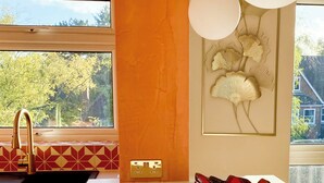 A modern kitchen with a large window, a sink with a gold faucet, and a decorative wall piece. - St Albans Gem: Stylish Flat, Balcony, Easy Commute (St Albans)