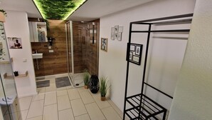 Un baño moderno con cabina de ducha de vidrio, suelo de madera y techo verde.