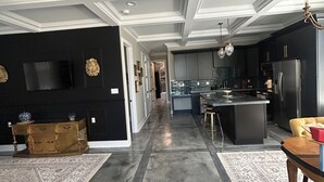 Una cocina moderna con armarios oscuros, una isla central y un comedor con mesa y sillas.
