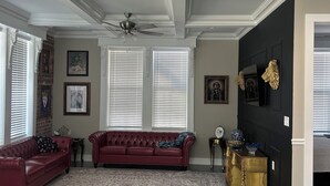 A spacious living room with a red sofa, a patterned rug, and a ceiling fan.
