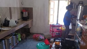 A compact kitchen with basic amenities, including a stove, sink, and storage shelves.