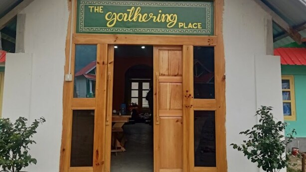 A building with a sign reading "The Gathering Place" and a colorful roof decoration.