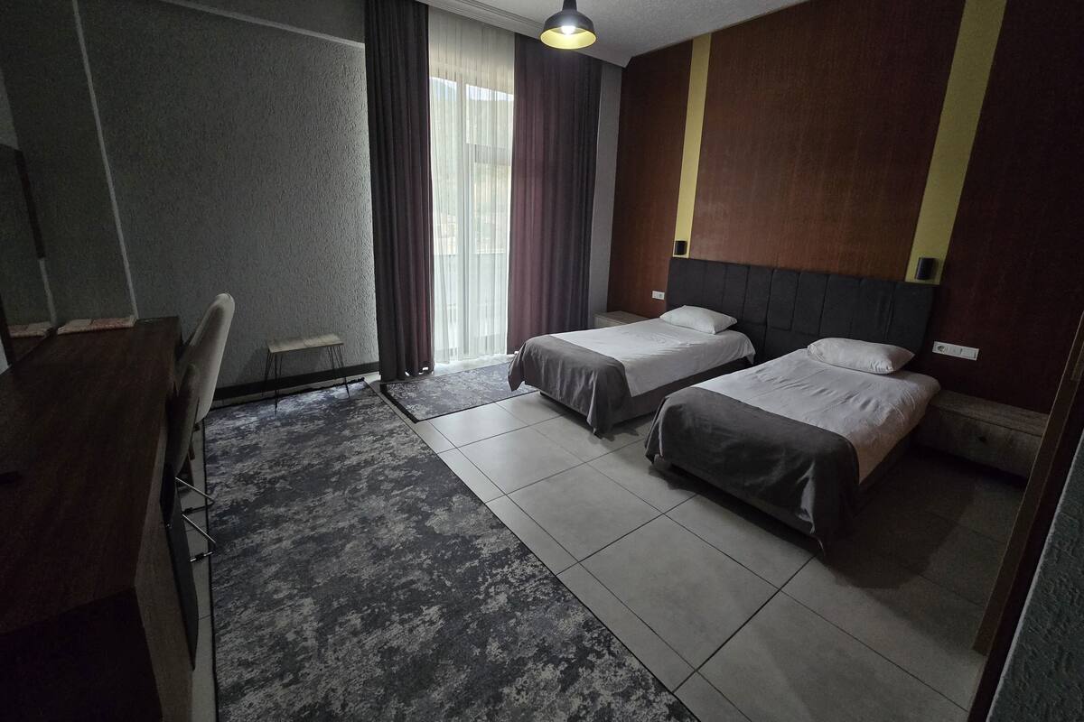 Een hotelkamer met twee bedden, een bureau en een stoel.