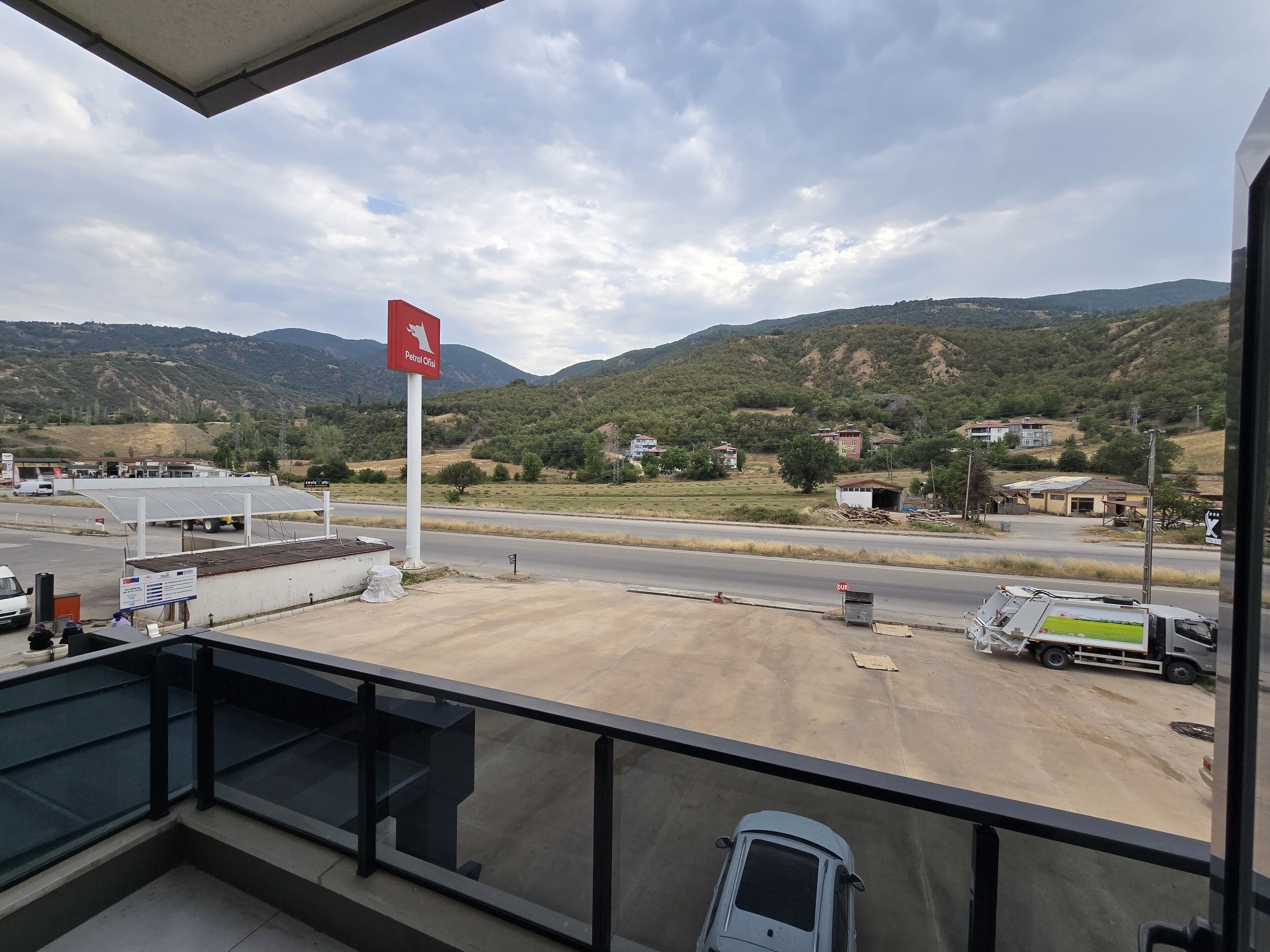 Un balcon donnant sur une station-service, une route et des collines lointaines.