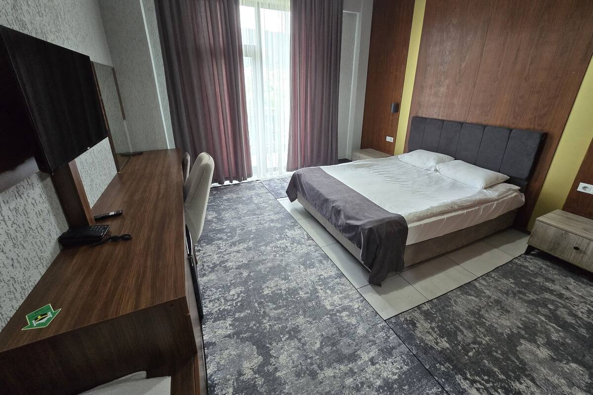 Een hotelkamer met een bed, een bureau, een stoel en een televisie.