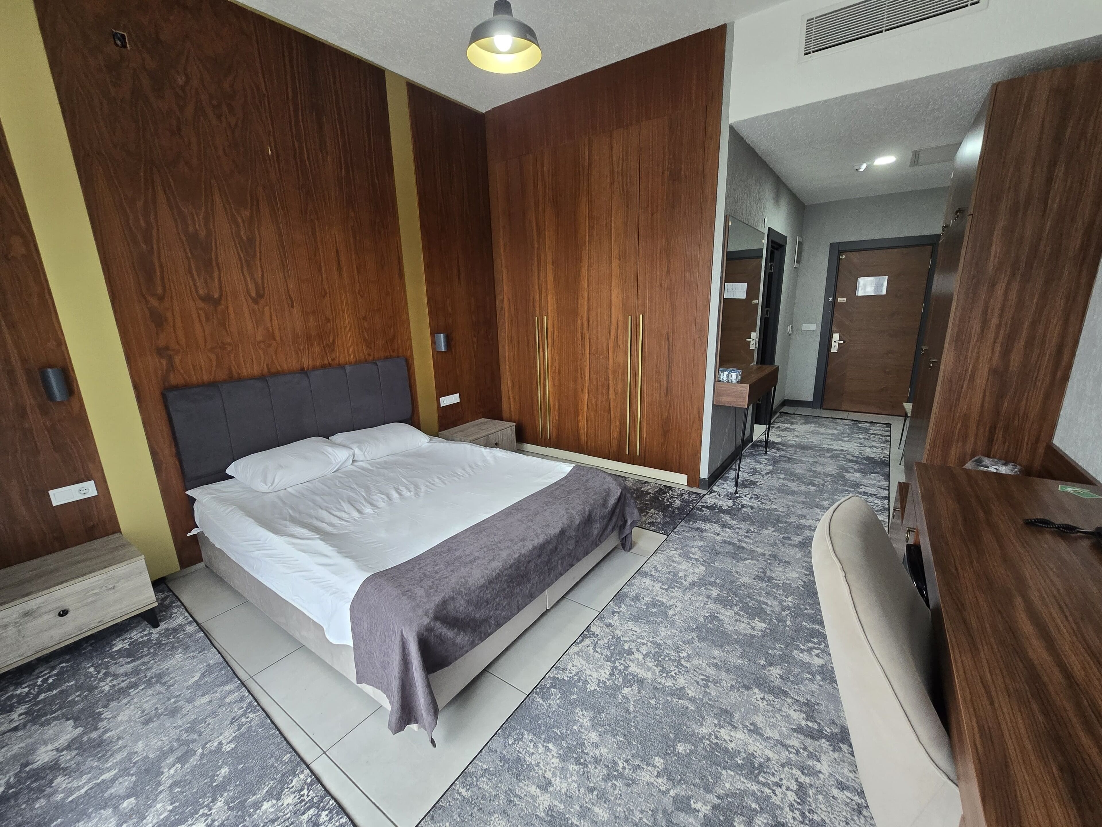 Un dormitorio con cama, armario de madera y tocador con espejo.