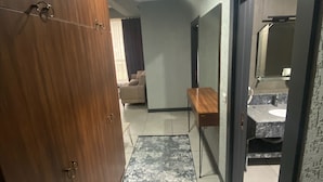 A hallway with a wooden wardrobe, a mirror, a small table, and a bathroom visible through an open door.