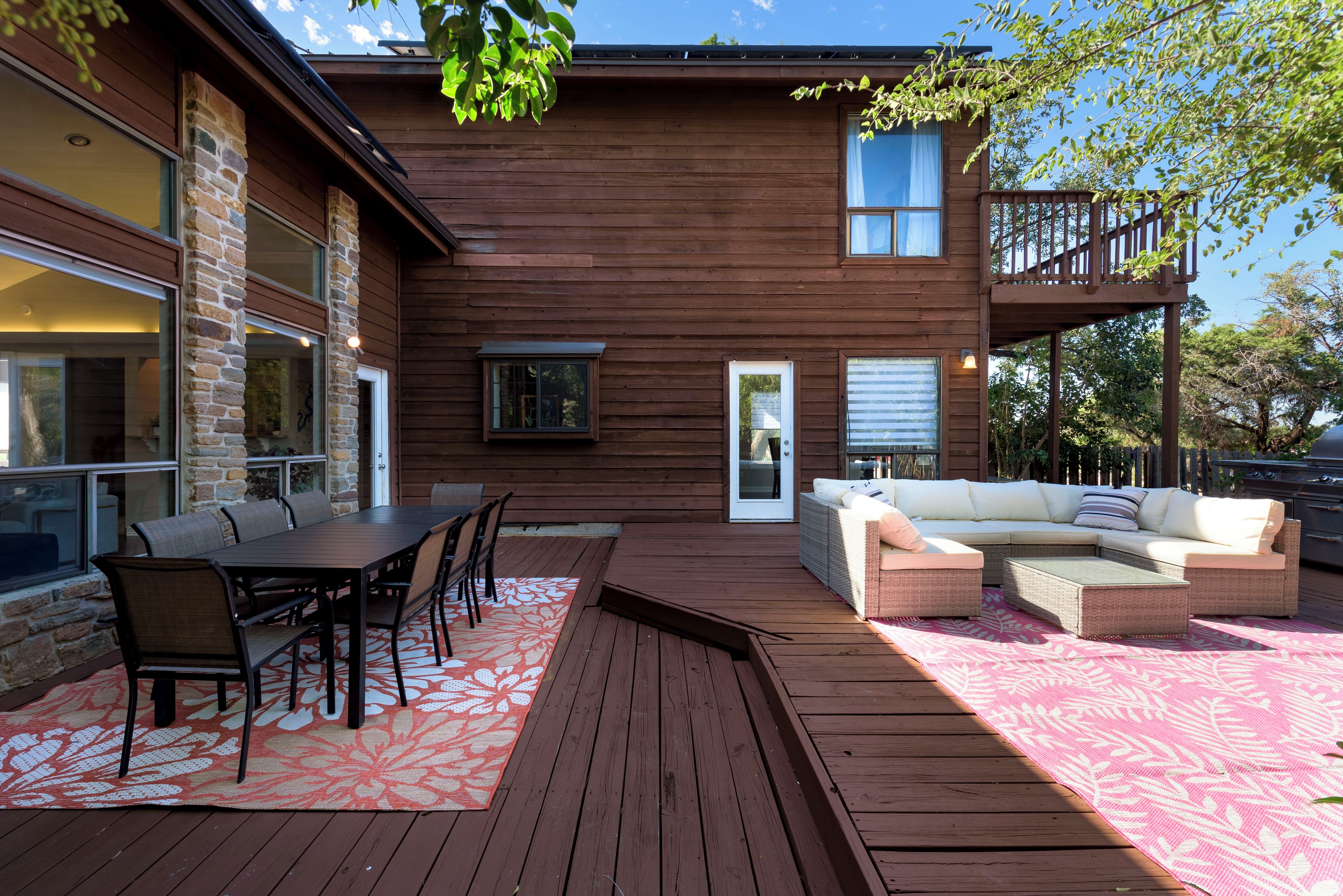 Una terraza de madera con una mesa y sillas de comedor, un sofá y un porche cubierto.