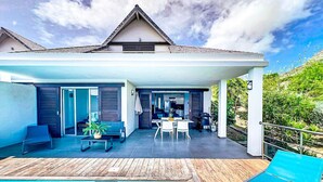 Ein modernes Haus mit überdachter Terrasse, Swimmingpool und Gartenmöbeln.