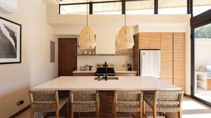 A modern kitchen with a large island, wooden chairs, and pendant lights. - Villa Colibrí, Villa Colibrí (Sámara)