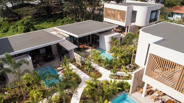 Un resort moderno con varias piscinas, zonas de estar al aire libre y exuberante jardinería.