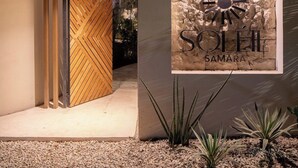 Entrada de un edificio moderno con una puerta de madera y un letrero que dice 'SOMETHING SAMARA'.