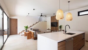 Una cocina moderna con una isla grande, armarios de madera e iluminación colgante.